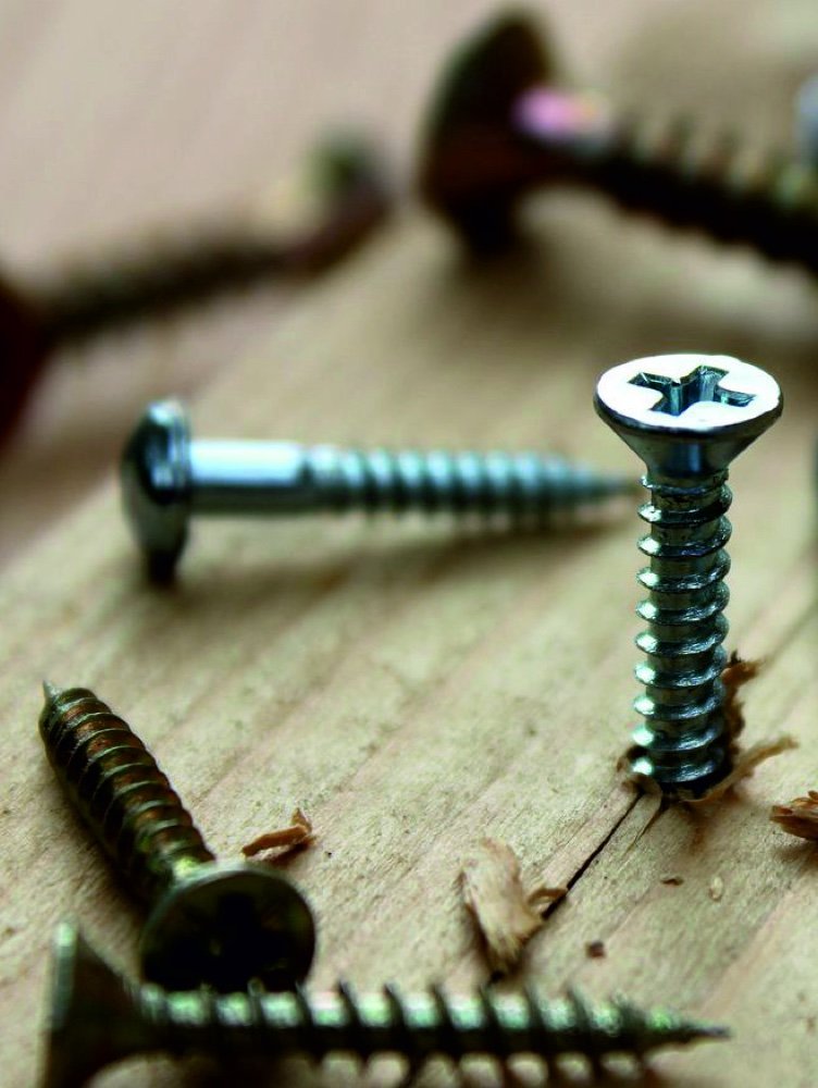 Zinc-plated and yellow-passivated screws on a timber work surface